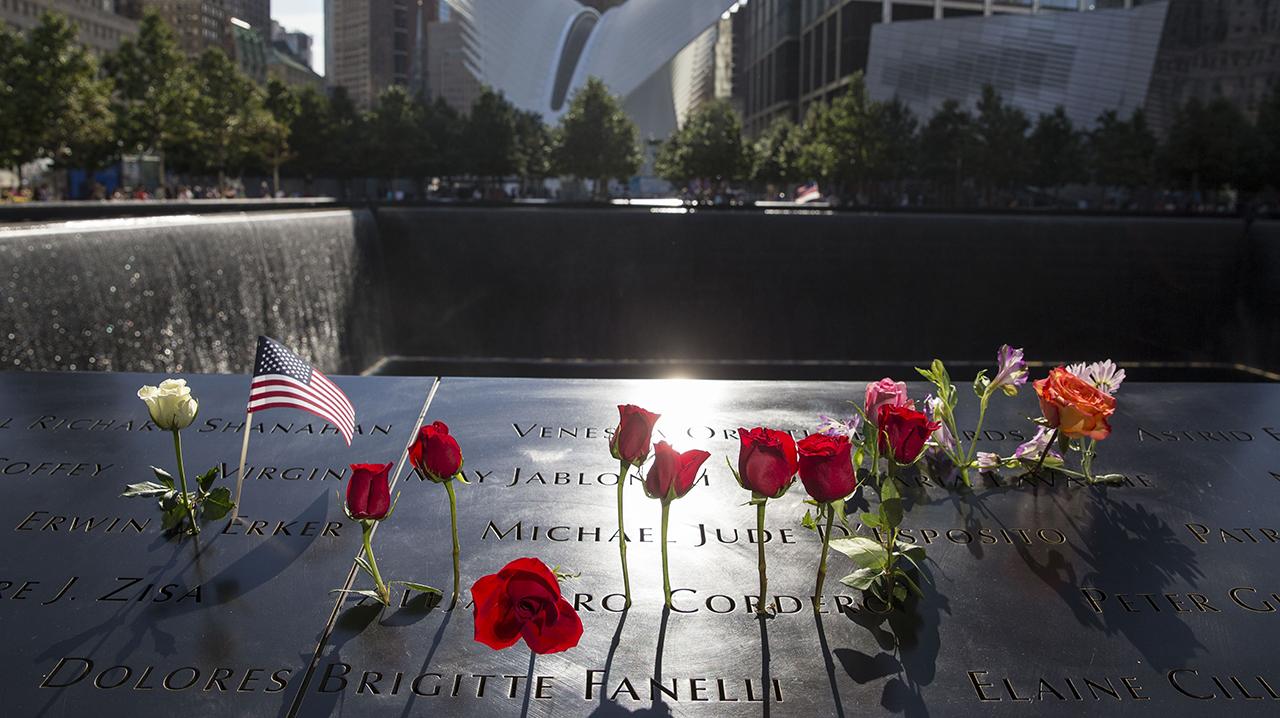 Flowers are left near names on the parapet.
